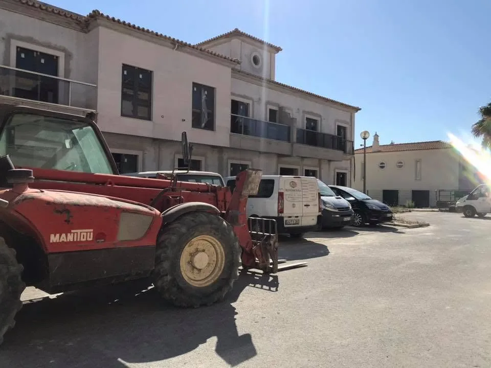 Empilhador Manitou à porta de um edifício em remodelação, com a carrinha da empresa